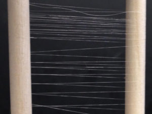 Horizontal parallel strands of synthetic spider silk stretched between vertical rods.